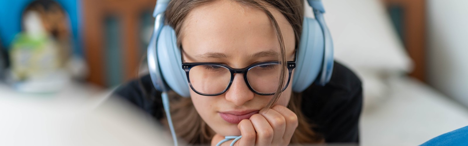 Young Person Wearing Headphones Using a Laptop for Online Learning at Home