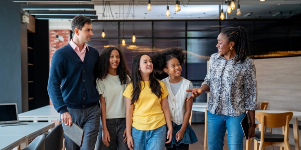two professionals guiding group of young work experience learners around the office